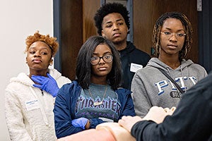 Delisa Davis, right, and other students watch a demonstration on locating the carotid artery and checking the pulse during the Rise Up conference.