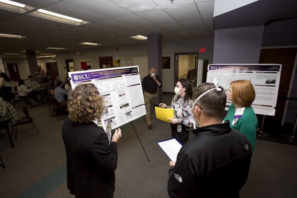 A group of four people examining a poster
