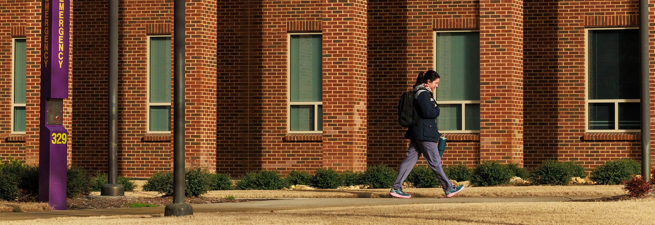 Student walking alone on ECU campus near emergency call box